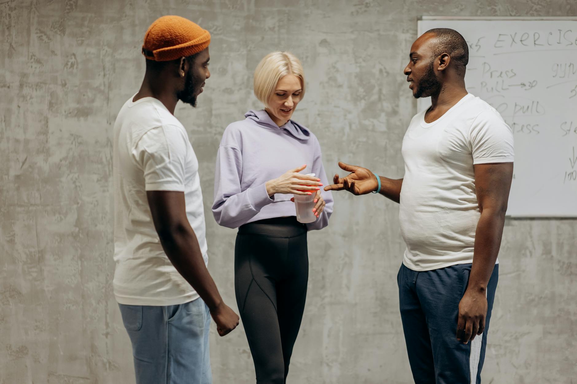 Three people discussing fitness plans in a gym setting, focusing on team motivation and healthy lifestyle.