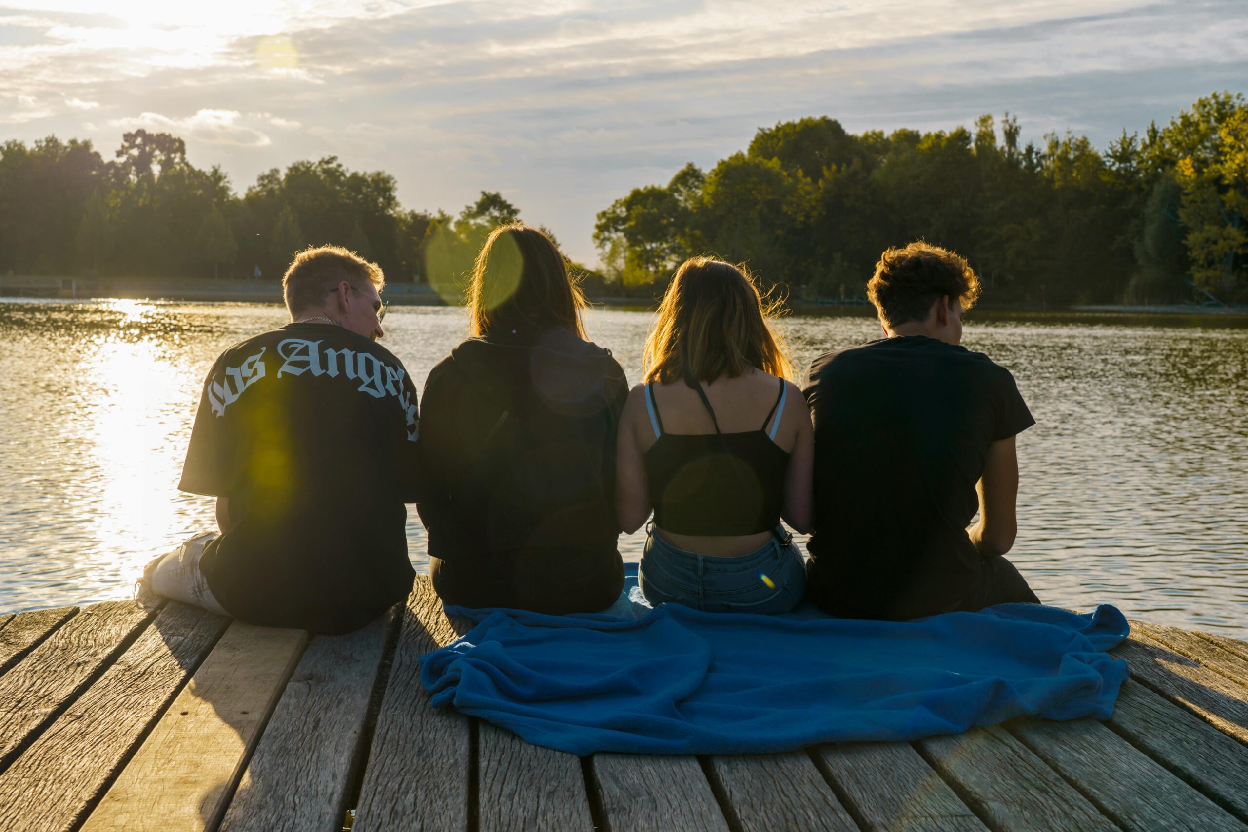 Teens enjoying friendship at a lake during golden hour, evoking tranquility and togetherness.